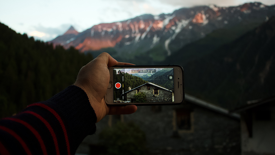 Filmmaker videoing mountain scenery.